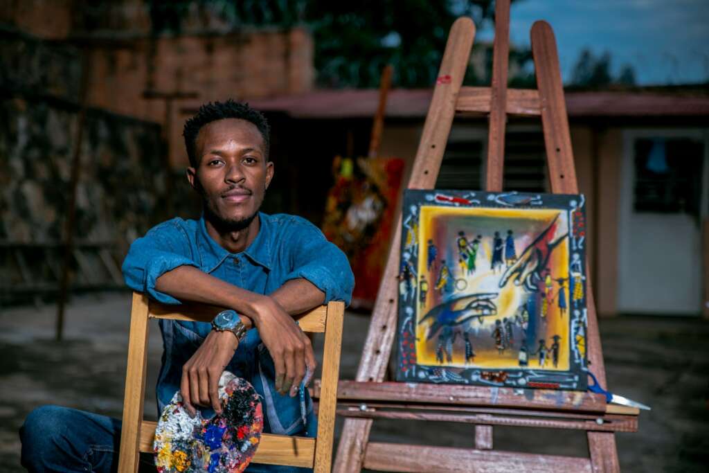 Painter sitting beside his colourful artwork